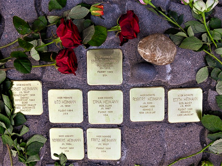© Georg Emme Auf dem Bild sieht man acht in den Boden eingelassene Stolpersteine. Rundherum liegen rote Rosen. © Georg Emme